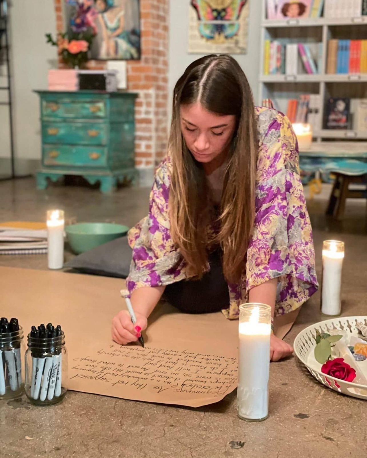 Tabitha writing on brown paper at The Bookshop in Buena Vista, Miami