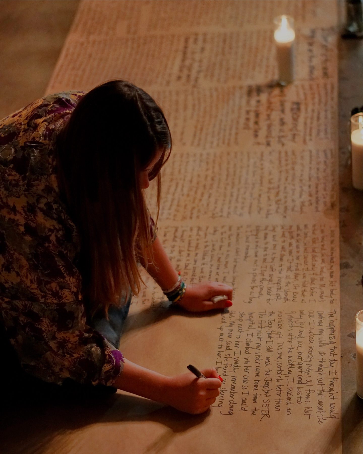 Tabitha writing her life story on a long roll of brown paper by candlelight