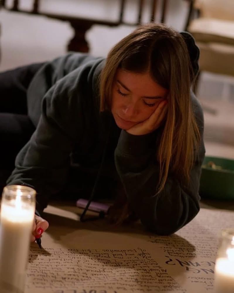 Tabitha lying on the floor, writing on brown paper