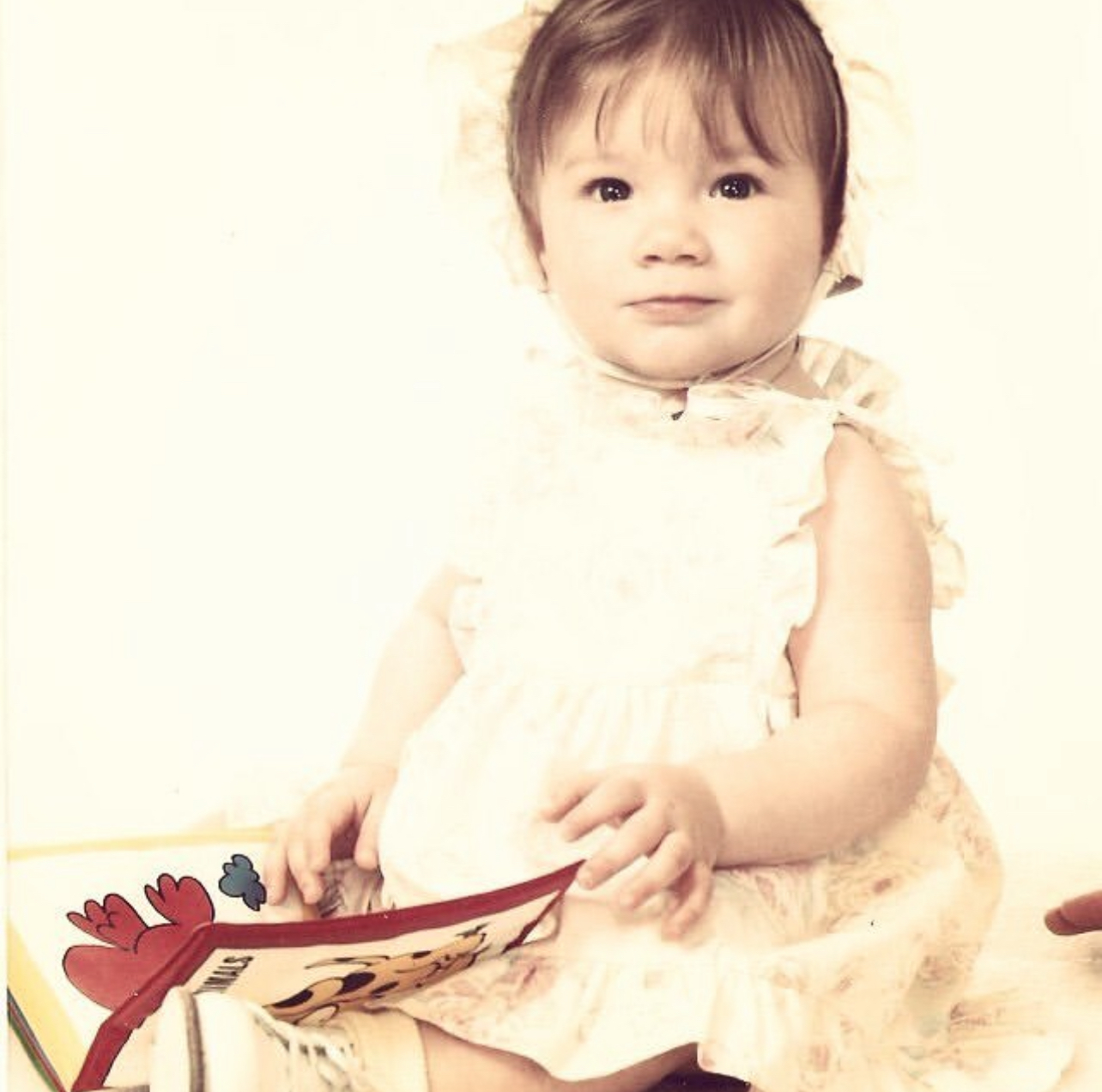 Tabitha as a baby holding a book